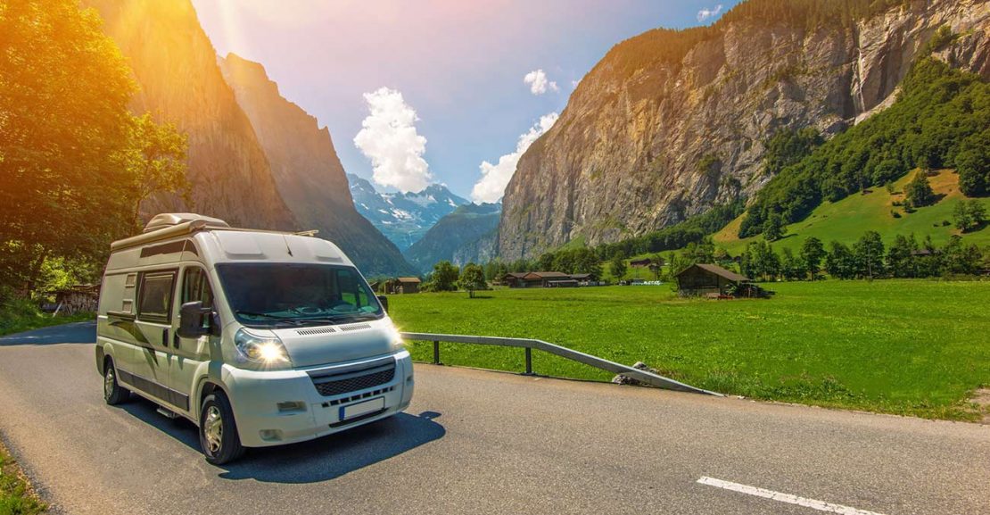 Autocaravana en carretera abierta con paisaje natural, mostrando la libertad de viajar y explorar sin restricciones.